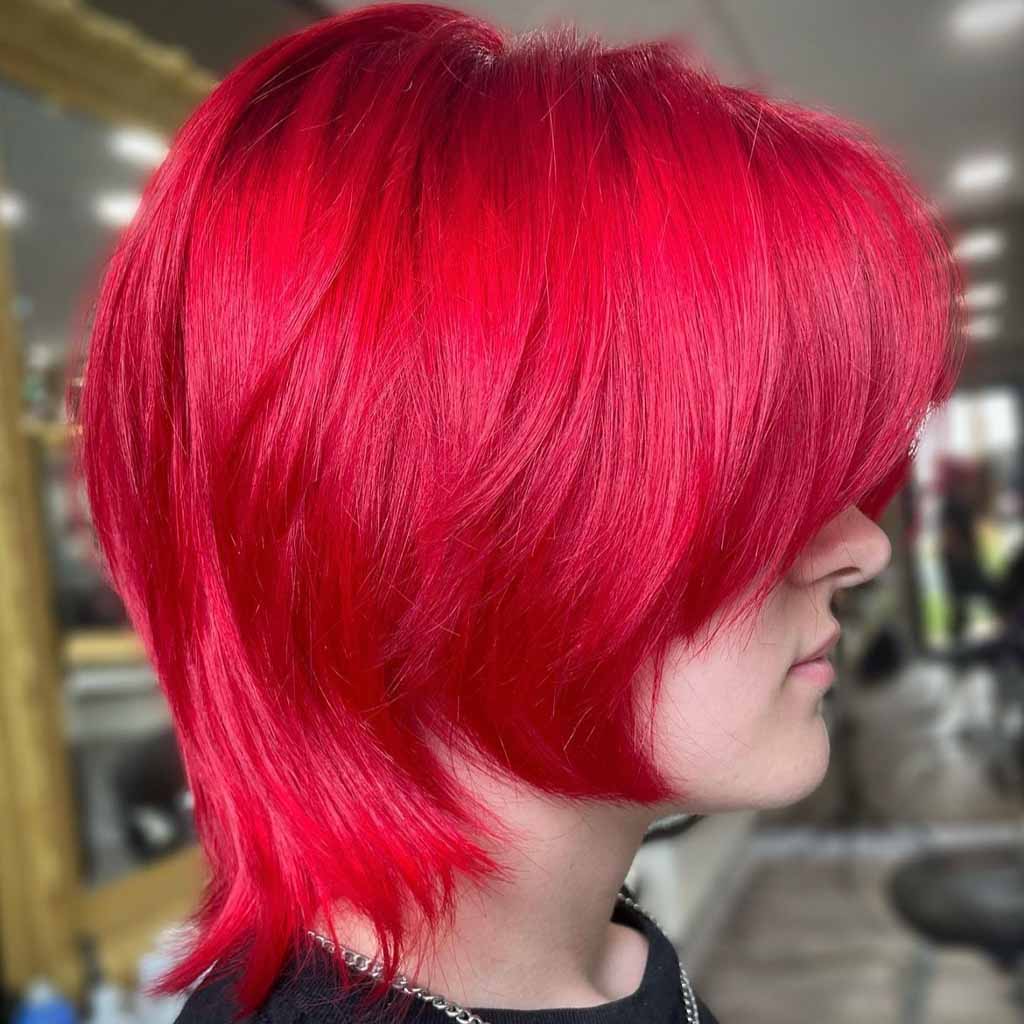 Side pose of a girl with red pixie wolf cut, wearing a neck chain and black tshirt