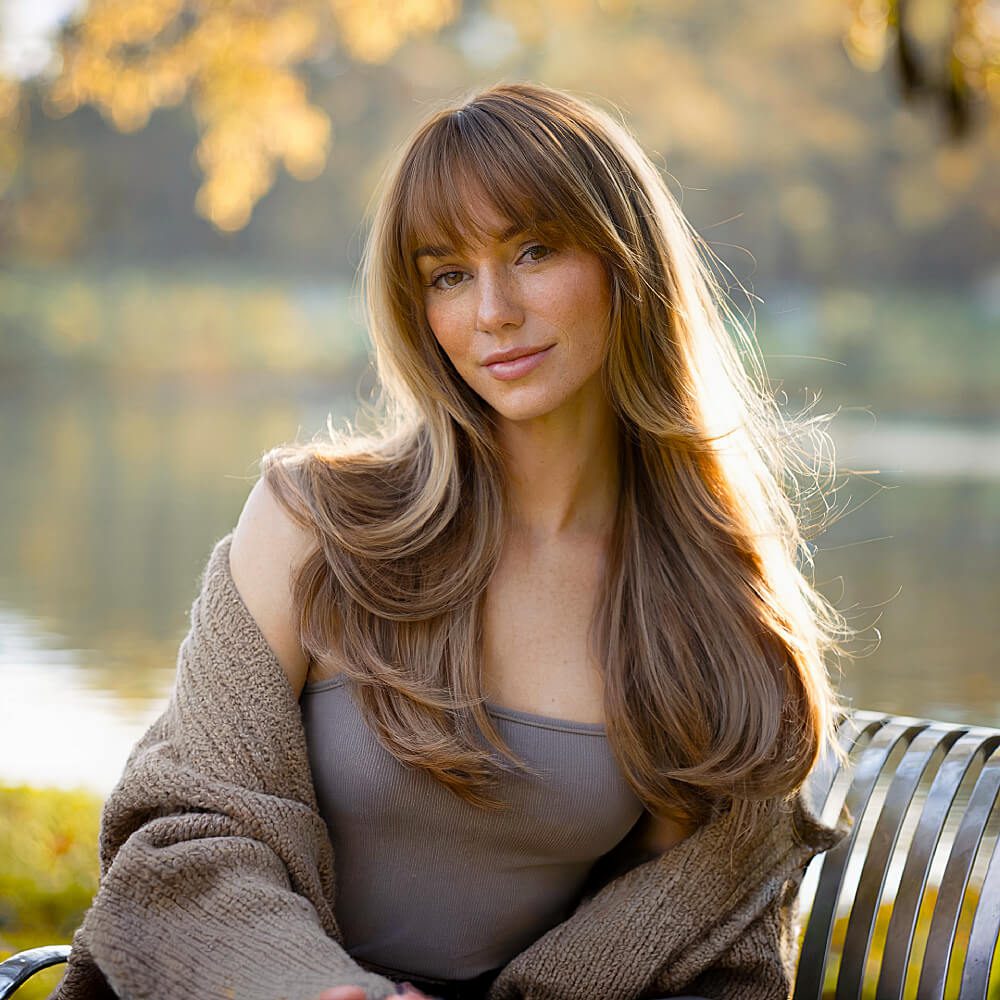 Long, soft layers with curtain bangs for a voluminous, feathered effect, enhancing movement and dimension